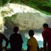 Vorschau: Vier Jugendliche von hinten aufgenommen, im Hintergrund eine Grotte aus weißem Fels, unten ist türkisfarbenes Wasser zu sehen. Foto: Edna Taff