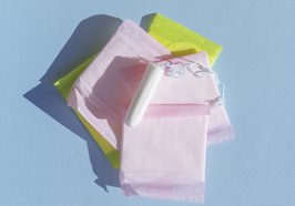 Stapel bunt verpackter Binden und darauf ein Tampon. Foto: freepik